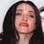 Pixelated close-up of a person with long dark hair, closed eyes, and a neutral expression against a light background.
