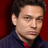 Static pixelated image of a person's face and upper torso against a solid red background, with visible dithering and low-resolution rendering artifacts.
