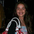 Pixelated photo of a person with long dark hair holding white and red objects against a black background, surrounded by bright pink text on solid red.