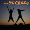 Silhouettes of two figures jumping against a sunset sky with orange text reading --be CRAZY above them.