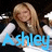 Pixelated image of a person with long light brown hair wearing dark clothing, overlaid with blue text reading 'Ashley' against a black background.