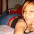 A person with light brown hair lies on a bed with red and blue pillows, wearing a dark top with red and yellow stripes, in a pixelated image.