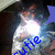 A pixelated image of a person in a white shirt with blue text overlaid, showing a bright light effect on the chest area.
