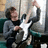 A pixelated image of a person holding a white electric guitar, with red text on pink and gray backgrounds.