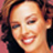 Pixelated close-up of a smiling person with curly hair against a pinkish background, rendered in low-resolution 48x48 pixels.