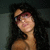 A person with long dark hair and red-tinted glasses appears in a of four , with the bottom-right empty