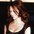 A pixelated image of a person with brown hair wearing a dark sleeveless top against a dark background.