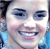 Pixelated close-up of a smiling person with light skin, blue eyes, and dark hair, wearing a blue garment with light reflections.