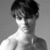 Black-and-white pixelated image of a person with short dark hair, light skin tone, and visible neck and shoulder area against gray background.