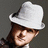 Pixelated image of a person wearing a white fedora and dark clothing against a gray background, with blue containing text