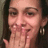 A person with long dark hair and hoop earrings covers their mouth with a hand in three showing slight head movement