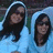 Two people in light blue hooded garments with dark hair, positioned side-by-side against a pink background with red text elements.