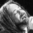 Black-and-white image of a person with long hair on left; blue background with green pixelated text reading 'Round here we talk just like lions But we sacrifice like lambs Round here shes slipping through my hands' on right.