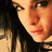 Pixelated close-up of a person's face with long dark hair, showing partial facial features and warm-toned skin under soft lighting.