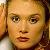 Static pixelated image of a person's face with light brown hair, neutral expression, and warm-toned skin under soft lighting.