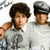 Two pixelated figures in light gray shirts, one with dark curly hair and the other wearing a cap, positioned side-by-side against a white background.