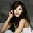 A pixelated static image shows a person with long dark hair wearing a sleeveless top, holding their hand near the face against a gray background.