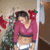 A pixelated image shows a person in a pink long-sleeve crop top and white shorts standing near a green plant with red flowers, holding a red object.