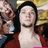 A pixelated image of a person with long dark hair wearing a red top and choker necklace, set against a yellow background with partial text "BP" visible.