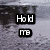 Static pixel art displays two black rectangular blocks with white text on a gray textured background; the top block reads 'Hold' and the bottom block reads 'me'.