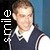 Pixelated static image of a person in a dark jacket with white trim, standing against a dark background with blue tones, featuring vertical white text on the left side.