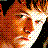 Pixelated close-up of a person's face with fiery orange and red tones, showing partial features against a dark background.