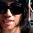 Pixelated close-up of a person with dark hair and light skin, partially obscured by a vertical light-colored object on the right.