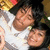 Two people in a close embrace, one with dark hair and light skin wearing white clothing, the other partially visible with dark hair.