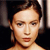 Pixelated close-up of a person with short dark hair, light skin, and a neutral expression against a dark background.