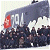 A pixelated static image shows a dark blue train with white smoke, red accents, and visible text on its side, set against a light background.
