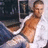 A pixelated image of a shirtless person in a white robe lying on a bed with red background and text overlays.