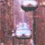 Pixelated image of a dark-colored hourglass with light-colored sand flowing through its narrow middle section against a muted pinkish-brown background.