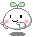 Pixelated character with white rounded body, green leaf-like top, pink cheeks, black eyes, and gray outline on gray background.