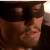 A pixelated close-up of a person's face with a neutral expression, wearing a dark cap and brown clothing, against a dark background with a light area on the right.