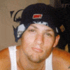 repeated images showing a person wearing a dark cap with red and white details, a white tank top, against a brown background