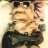 Pixelated image of a person wearing dark sunglasses and a dark jacket, with light-colored hair visible under the sunglasses.