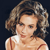Pixelated image of a person with curly brown hair wearing a white sleeveless top with red straps against a dark background.