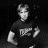 Pixelated grayscale image of a person in motion with indistinct facial features and partial text on clothing, set against a dark background.