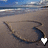 Beach scene with wave pattern in sand, two small heart-shaped icons at bottom right corner, one white and one black.