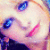 Pixelated close-up of a face with blue eyes, pink lips, and light skin tones against a soft pastel background.