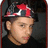 Pixelated close-up of a person wearing a red and white cap with dark brim, light skin tone, brown hair visible beneath the cap, neutral expression.