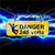 Yellow rectangular sign with 'DANGER HIGH VOLTAGE' text and lightning bolt symbol, suspended by wires against dark background with blue electric effects.