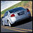 Pixelated static image of a blue car with red accents on water, set against grassy and sandy terrain under a light sky.