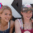 A pixelated image of a woman in a red and white top with dark straps, smiling while holding a black object near her face.