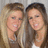 Two women with light and dark hair stand side-by-side, both smiling at the camera in a pixelated static image.
