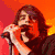 six distinct images: a person singing into a microphone, a person in a black jacket, a person with shoulder-length hair, a black-and-white crest, yellow text on black background, and three people standing together