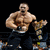 Pixelated static image of a muscular shirtless man with short hair holding a large trophy against black background.