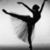 Black silhouette of a ballet dancer in mid-pose against light gray background, one leg extended horizontally with arms raised above head.