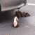 Animated duck icon with white head and brown body, positioned on gray surface near dark object.