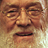 Pixelated close-up of a human face with closed eyes, furrowed brows, and downturned mouth against a light brown background.